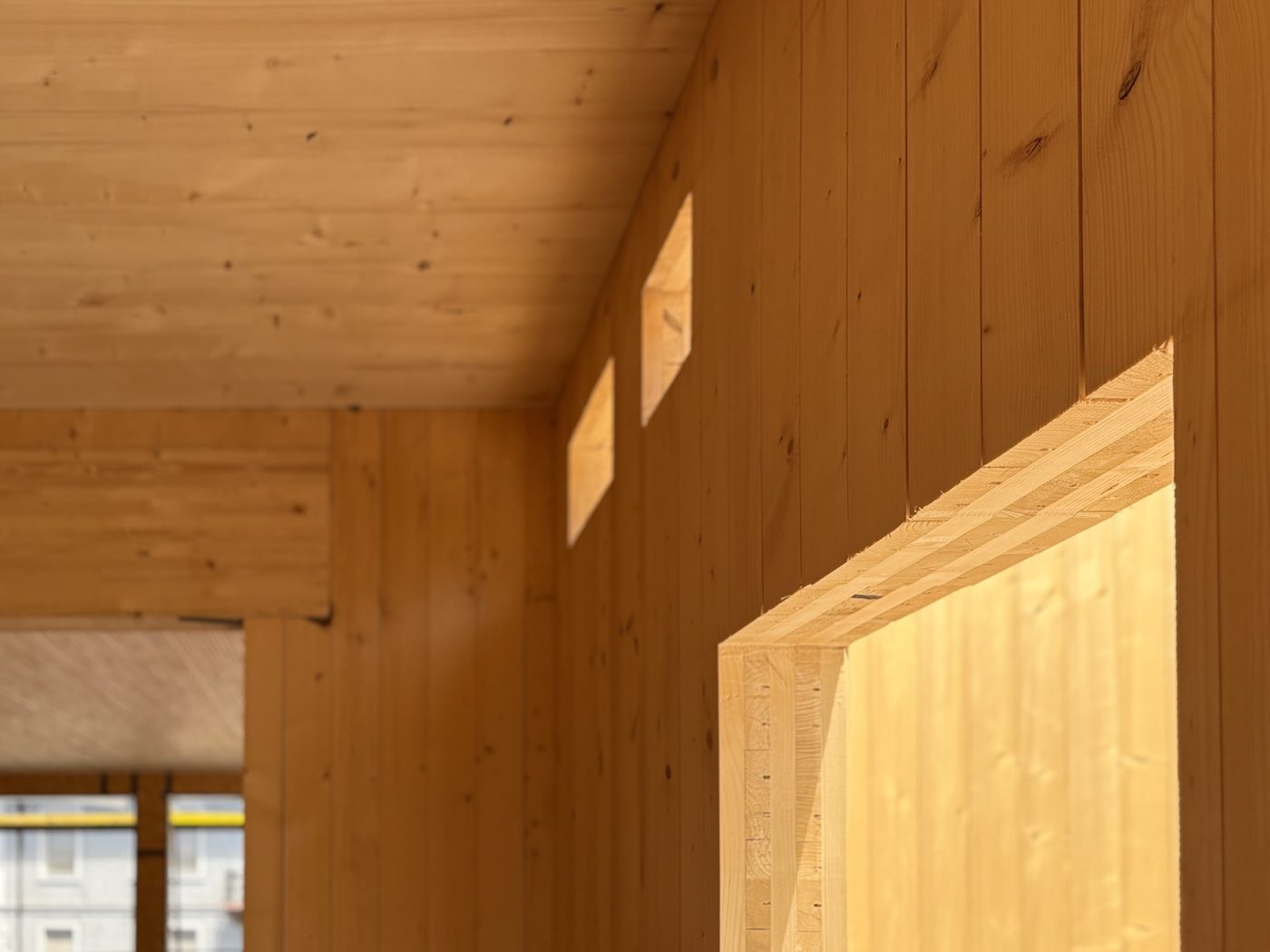 Interior of a building framed in cross-laminated timber, the panel lamination clearly visible in the layered edge at a wall opening.