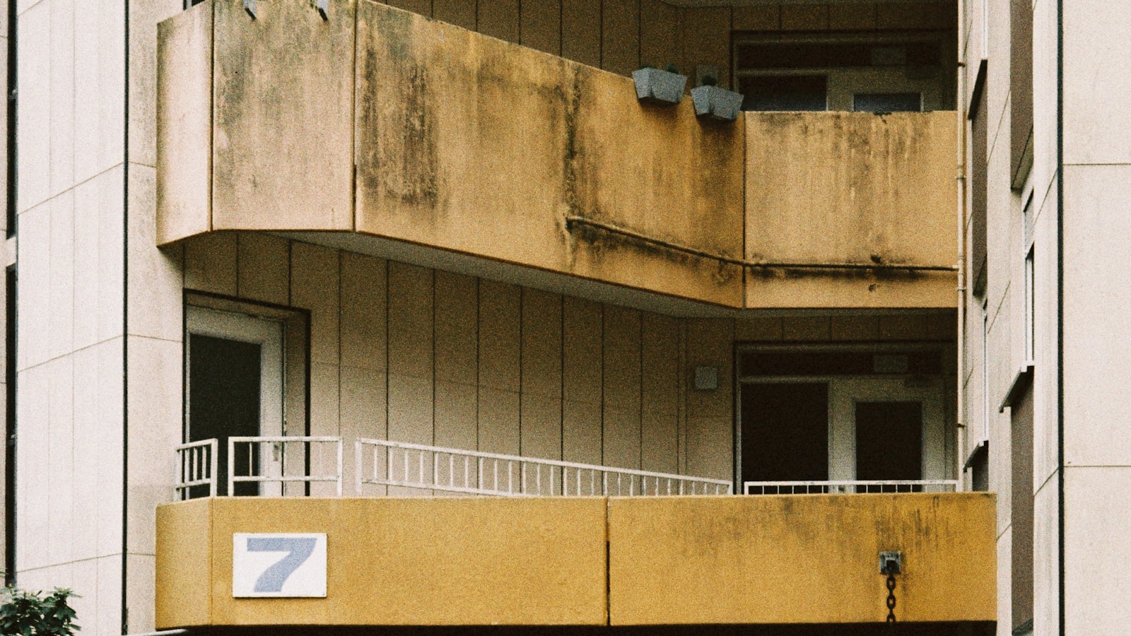 Weathered concrete apartment balconies with water staining down the parapet faces